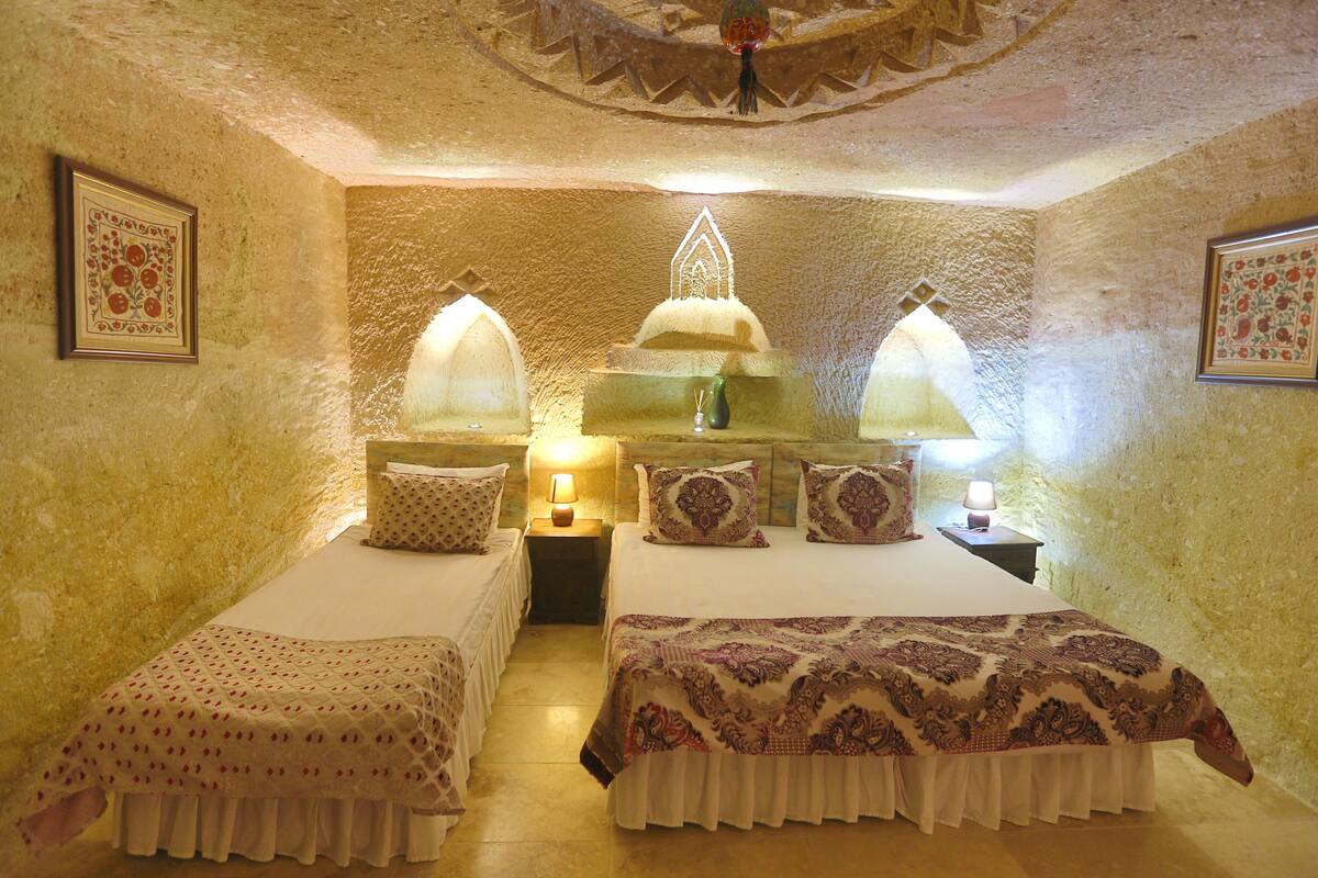 Ein Zimmer mit zwei Betten, jeweils mit einer anderen Bettdecke, einem Nachttisch mit Lampe und einer dekorativen Decke.