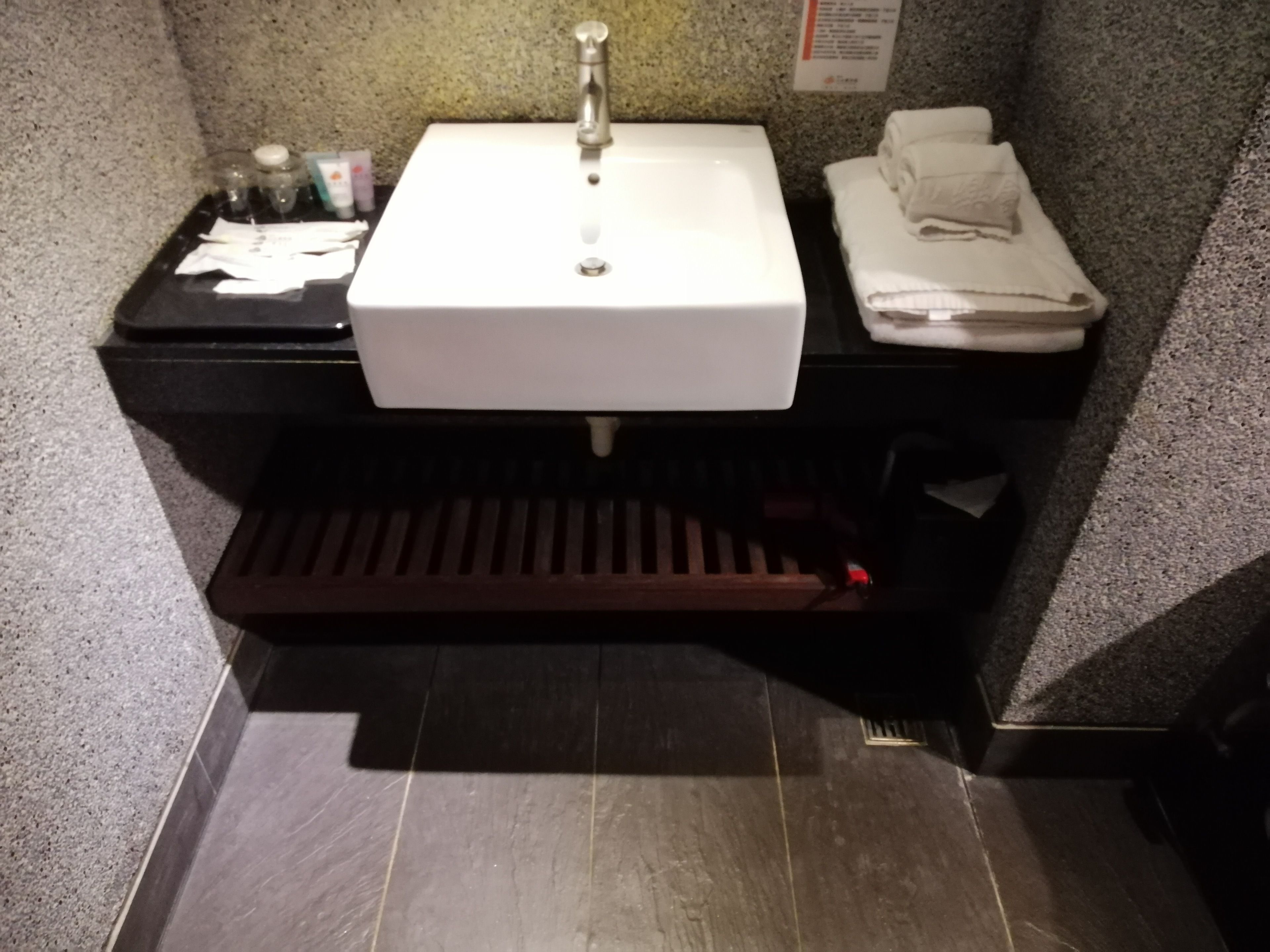 A bathroom with a white sink, a black countertop, and a towel rack.