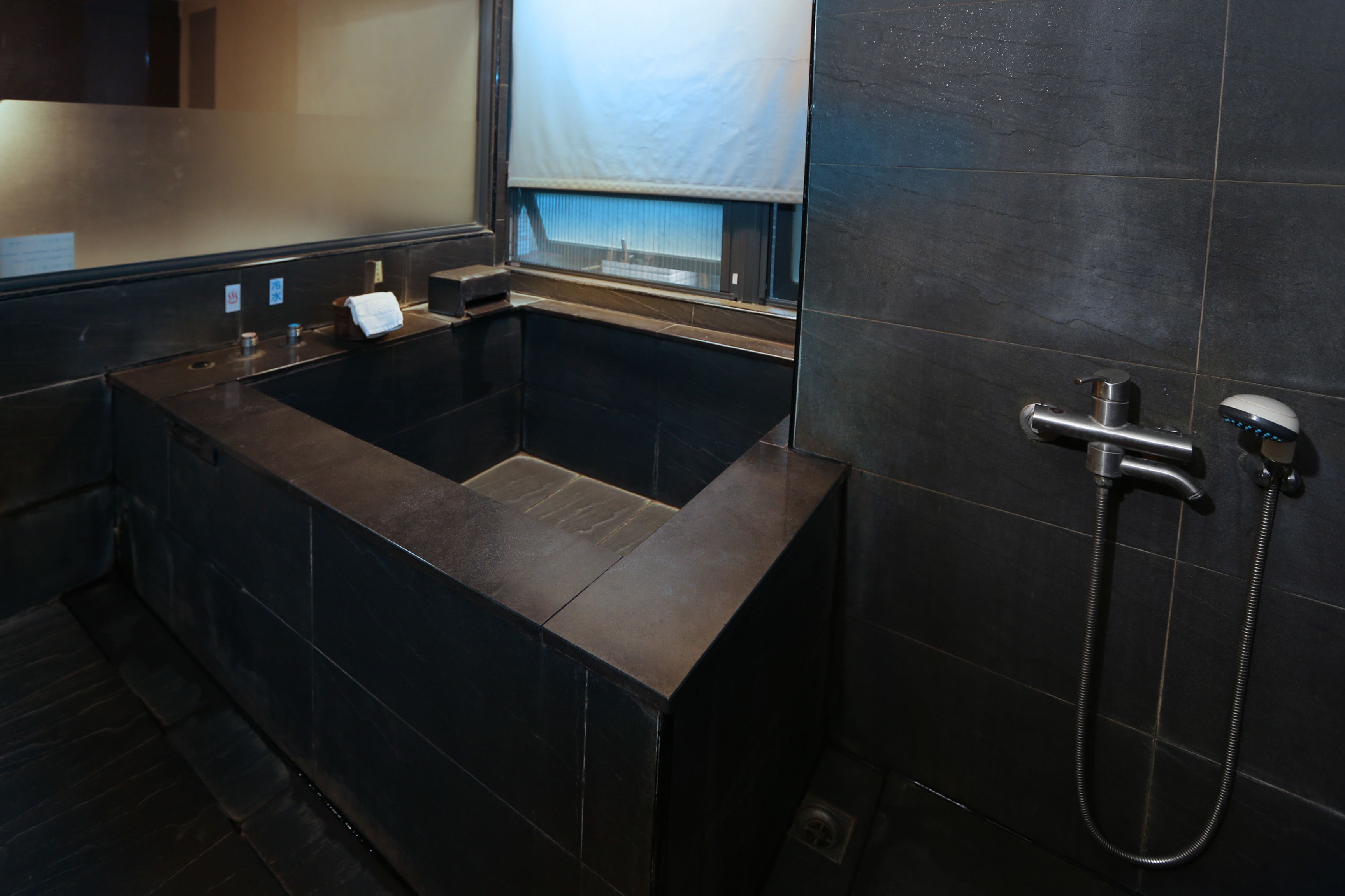 A modern bathroom with a freestanding bathtub, a handheld showerhead, and a towel rack.