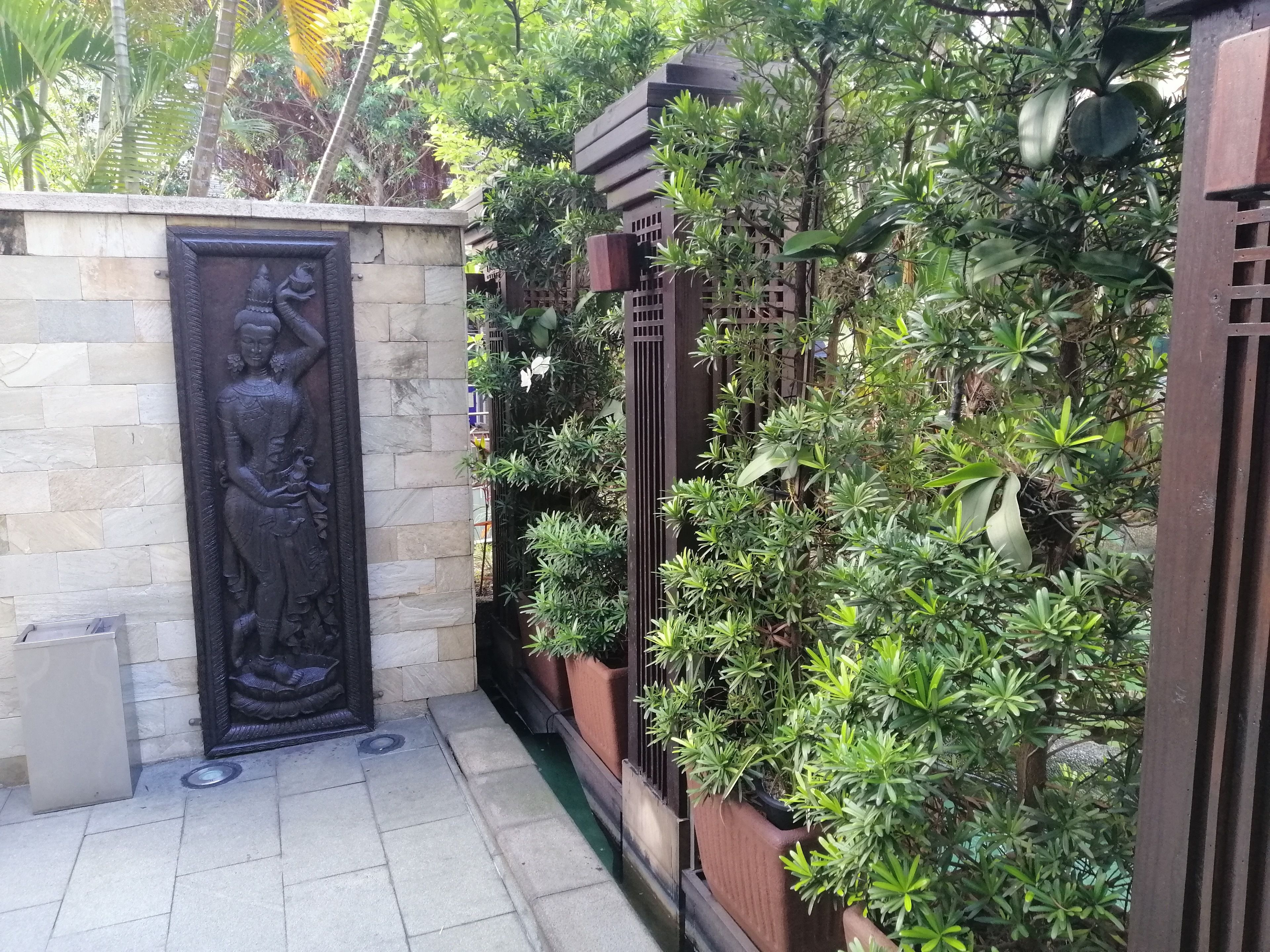 Un muro de piedra con un relieve, un patio empedrado y una variedad de plantas en macetas.