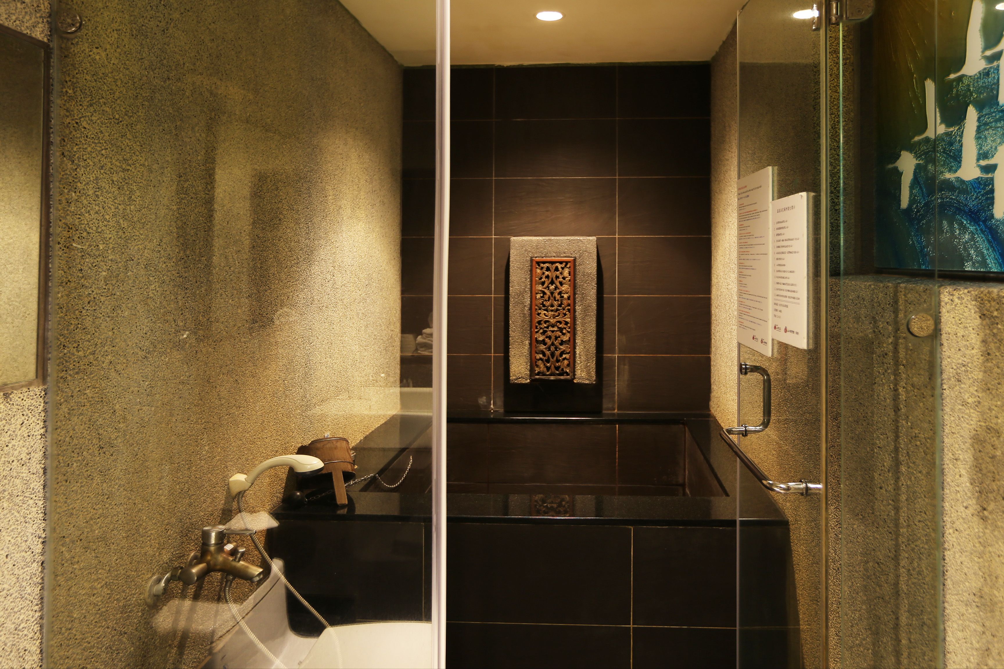 A modern bathroom with a glass shower enclosure, a towel rack, and a decorative wall panel.