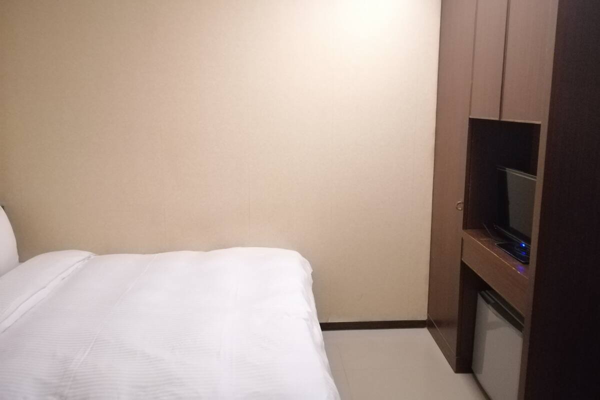 Hotellihuone, jossa on sänky, televisio ja vaatekaappi.