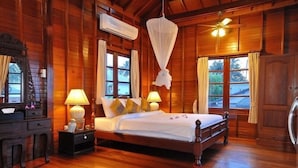 A wooden room with a bed, bedside lamps, a nightstand, and a window with curtains.