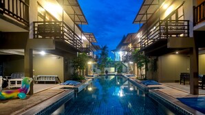 A swimming pool with a view of hotel buildings and a sunset.