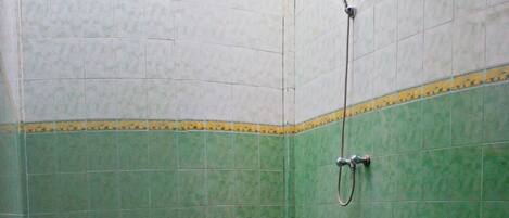 Pequeno box de chuveiro com azulejos verdes e brancos, um chuveiro e uma borda decorativa amarela.
