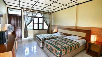 Habitación de hotel con dos camas, un escritorio, una silla, un ventilador y una ventana con cortinas.