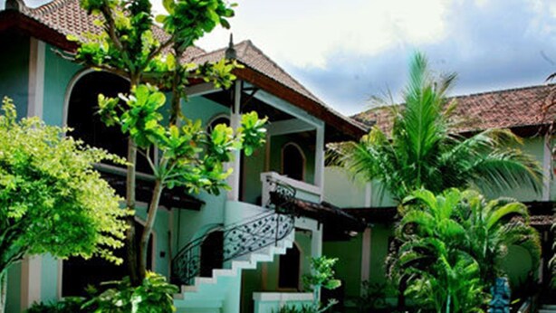 A pool surrounded by a lush garden with a staircase leading to a covered area.
