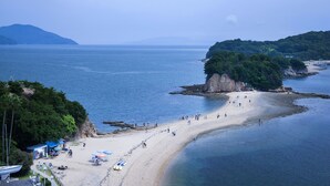 Una playa con arena, una pequeña cala y algunas embarcaciones.