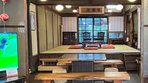 Una habitación japonesa tradicional con esteras de tatami, muebles de madera y un televisor.