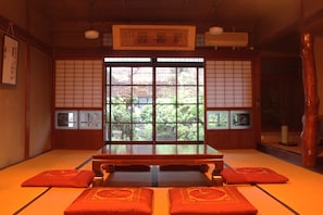 A traditional Japanese room with tatami flooring, a low table, and cushions.
