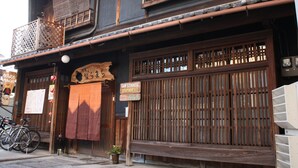 Un edificio japonés tradicional con fachada de madera, un letrero que indica una posada y bicicletas estacionadas afuera.