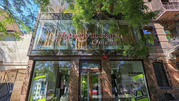 Un hotel boutique con fachada clásica, amplios ventanales y un cartel llamativo sobre la entrada.