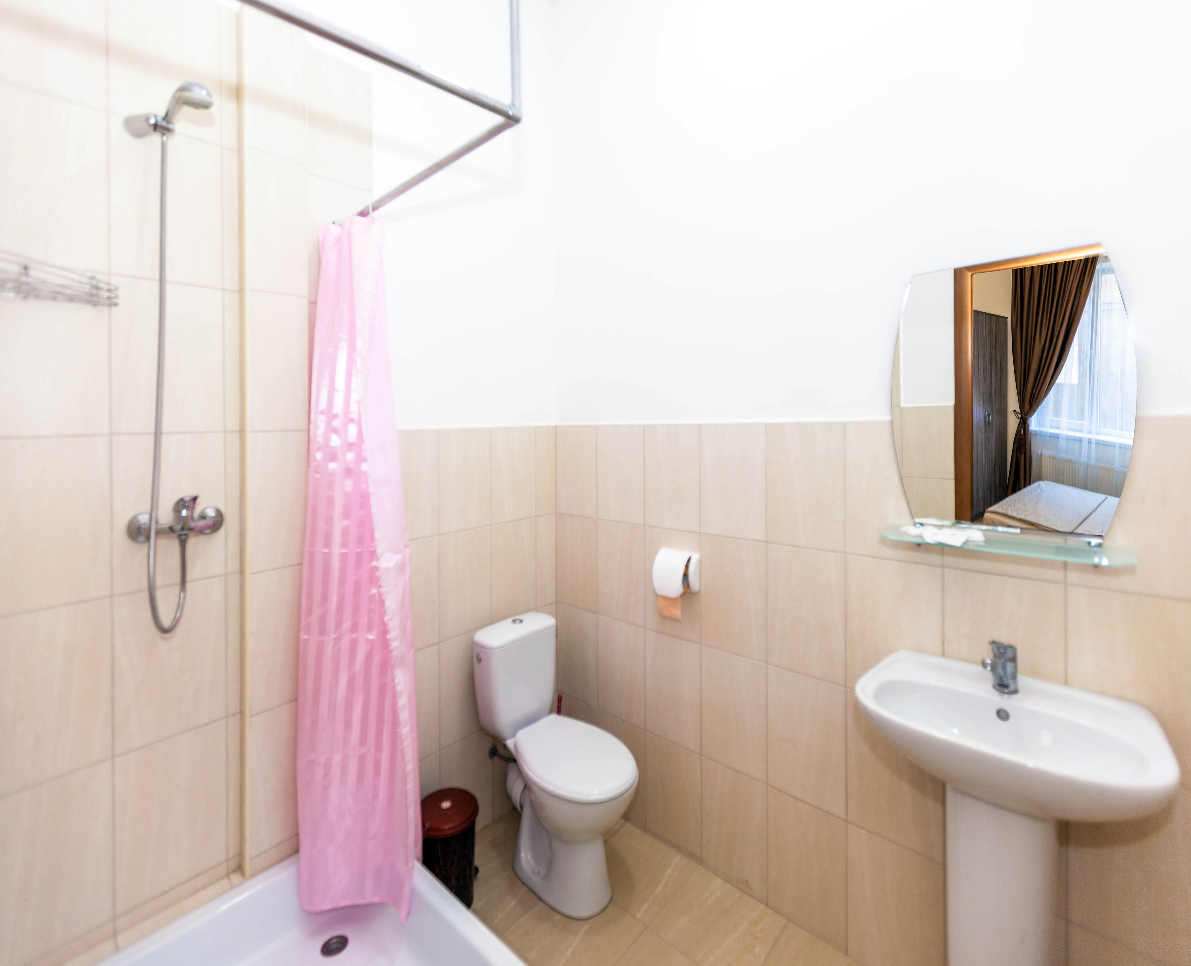 A bathroom with a shower, toilet, sink, and a mirror.