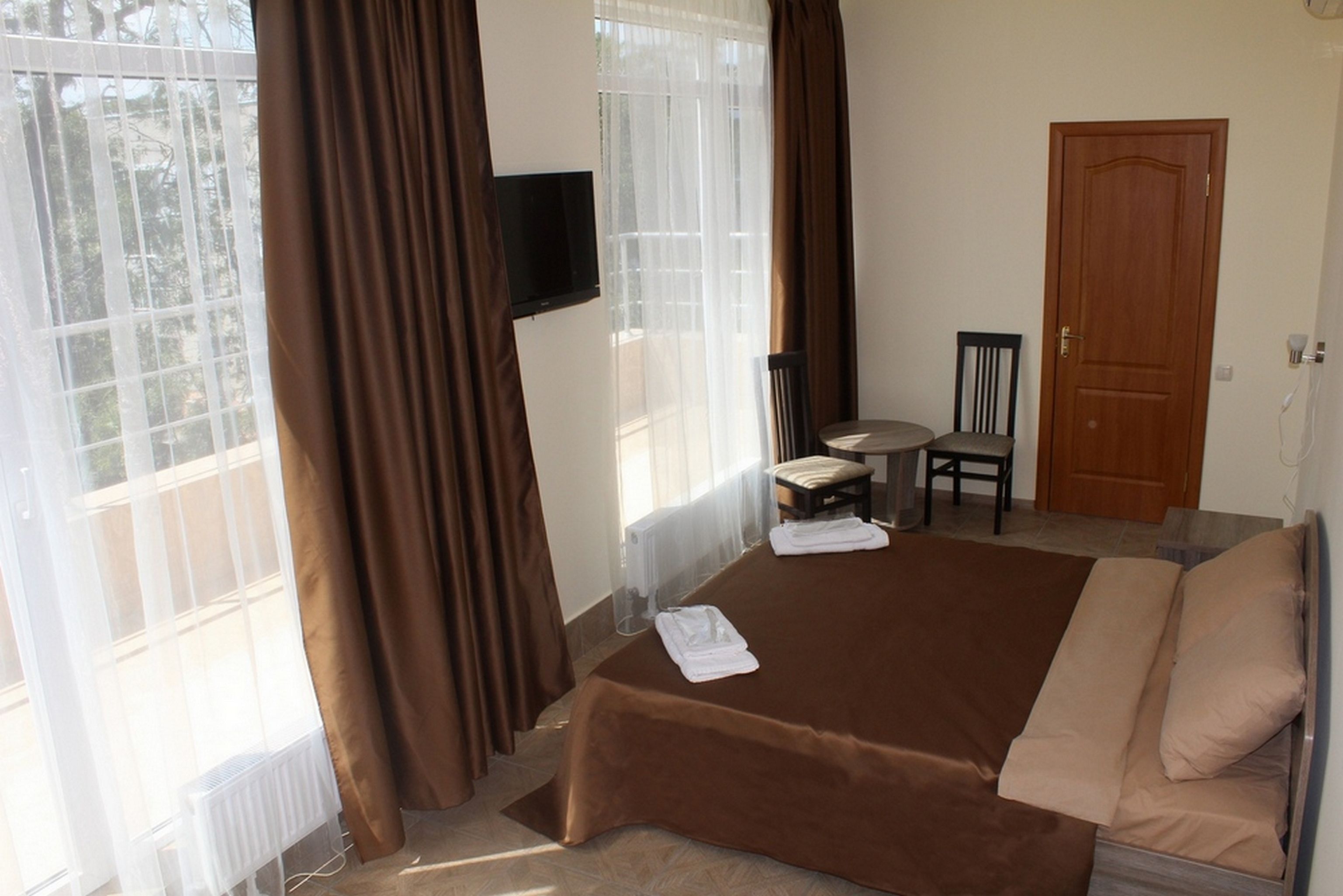 Una habitación de hotel con una cama, una silla, una mesita y un televisor colocado en la pared.