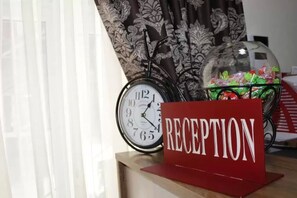 A reception area with a clock, a sign reading "RECEPTION," and a decorative glass dome with candies. - Hotel Arnautsky (Odesa)