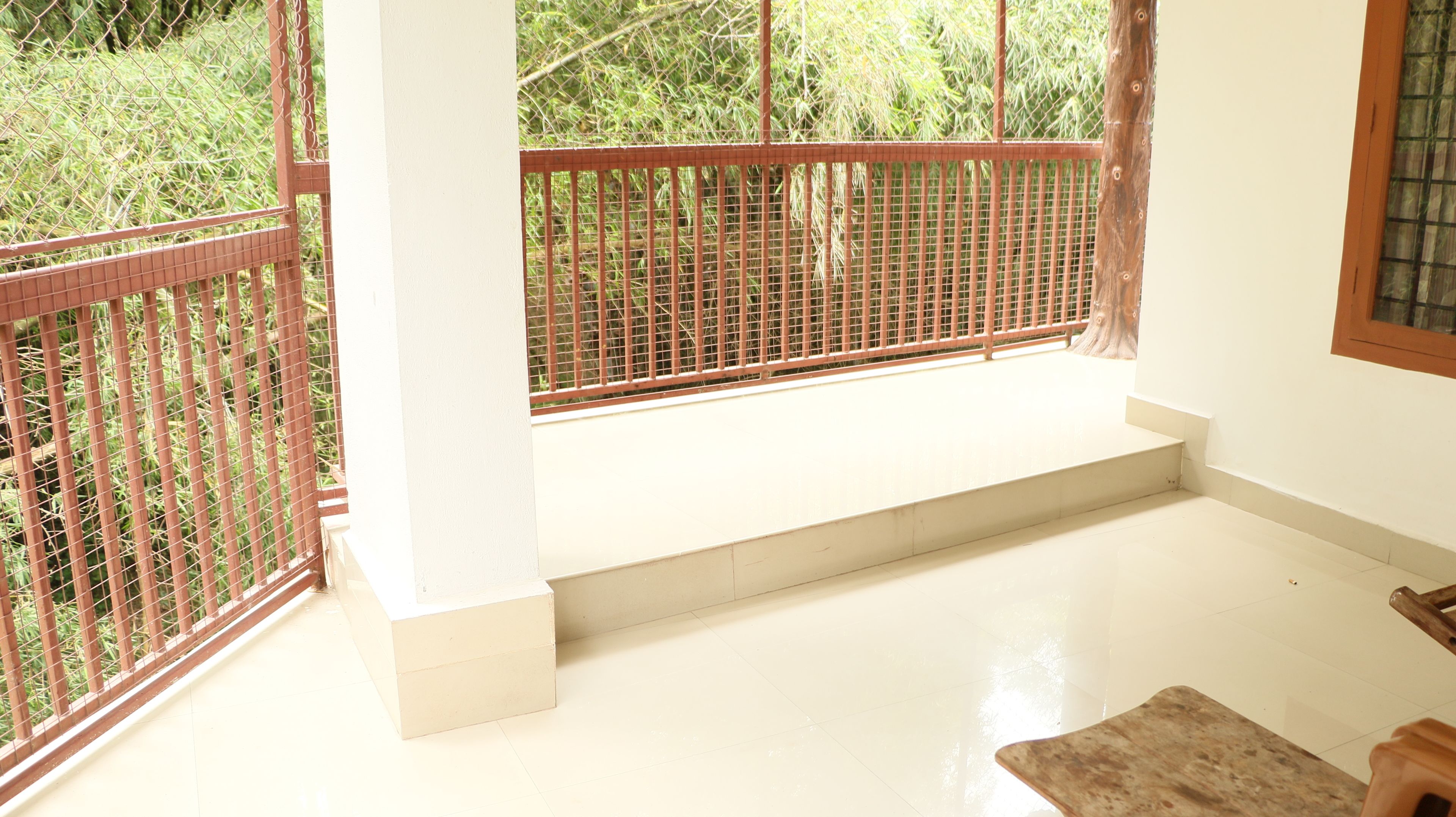 A room with a white floor, a wooden bench, and a metal railing.