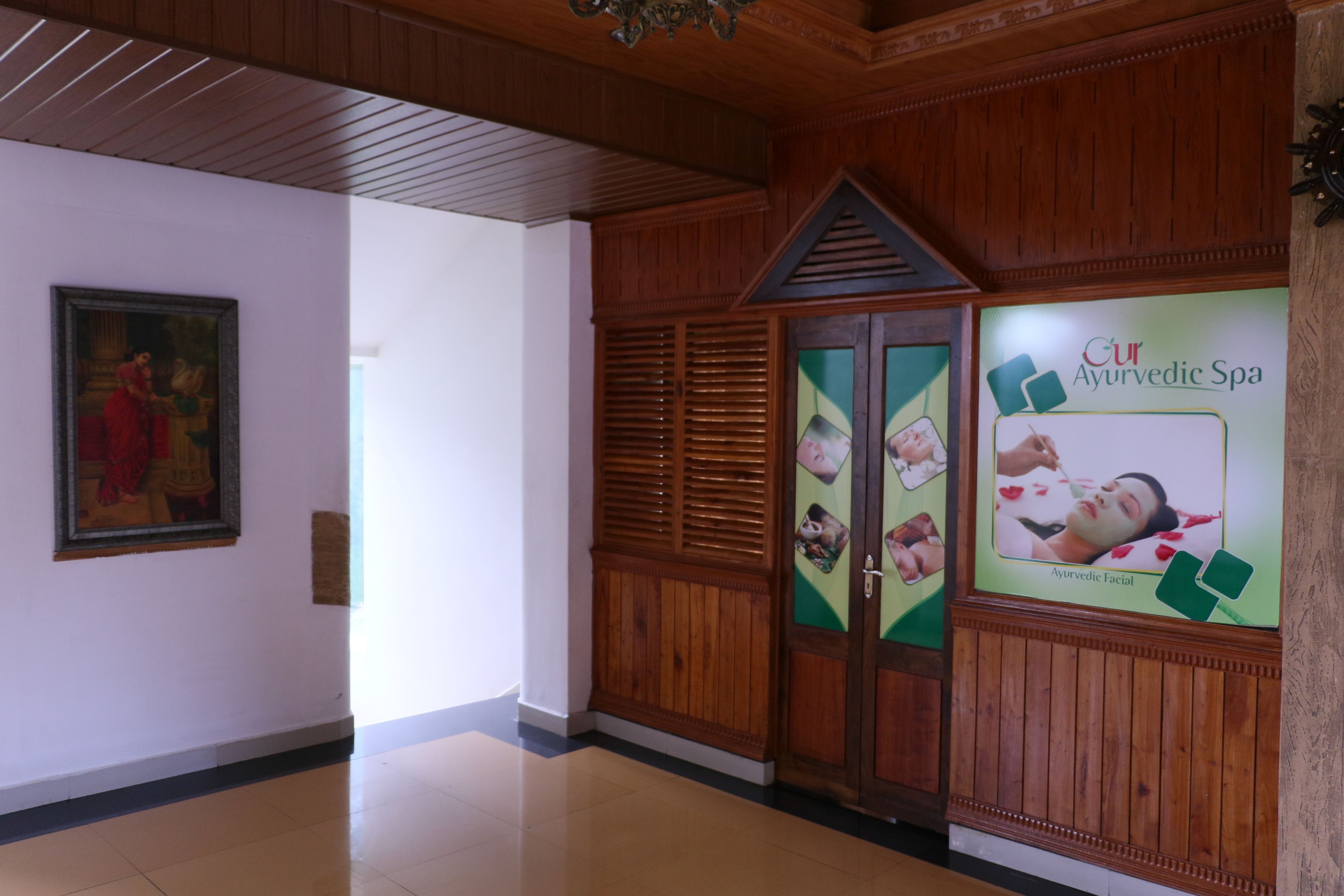 A hallway with wooden paneling, a framed painting on the left, and a spa advertisement on the right.