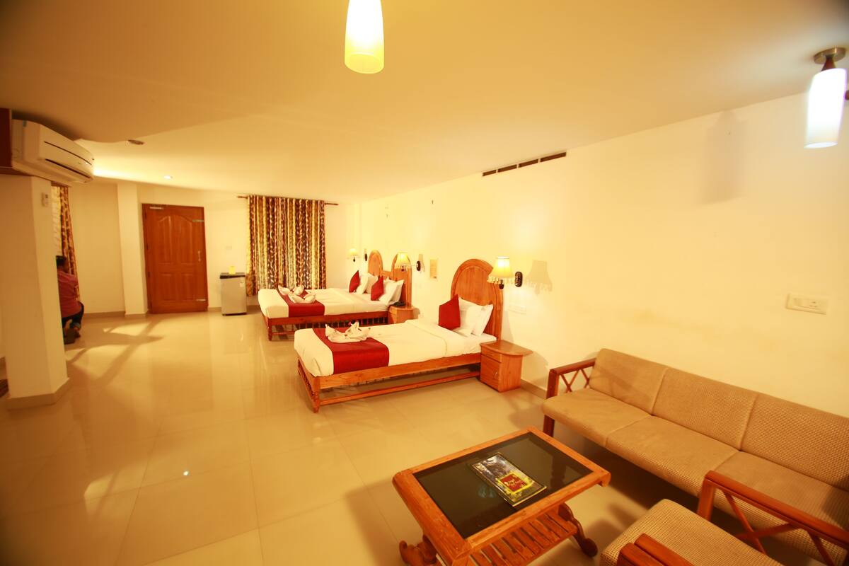 Una habitación de hotel con cama, sofá, mesita de centro y espejo.