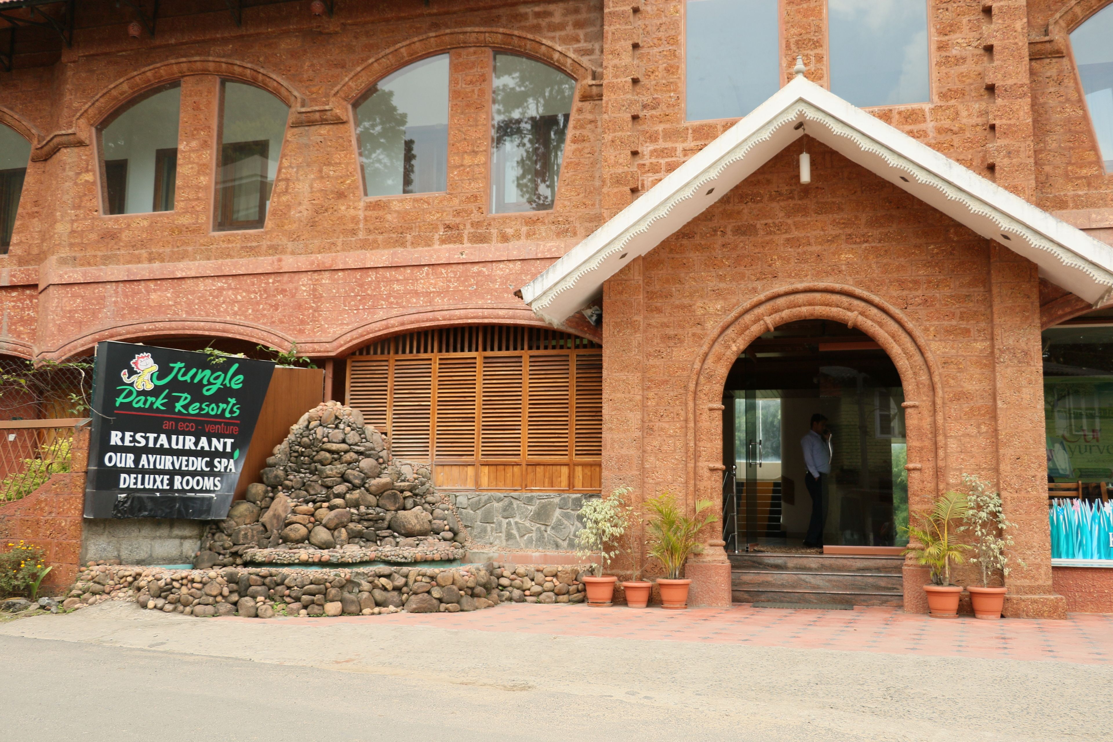 Edificio de ladrillo con un cartel que indica Jungle Park Resorts, un restaurante ayurvédico y un spa.