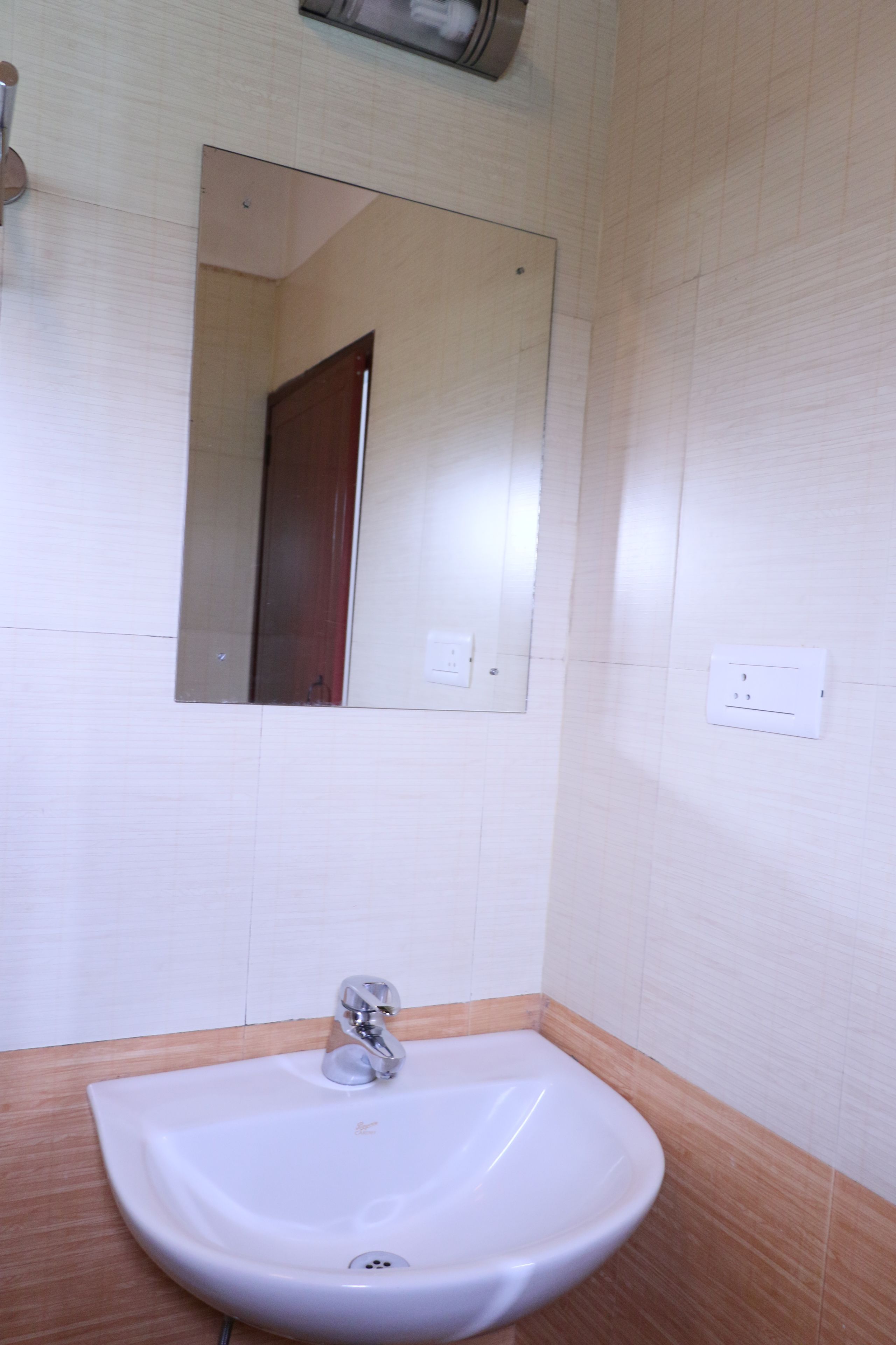 A bathroom with a white sink, a mirror, and a wooden vanity.
