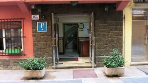 A building entrance with a glass door, a parking sign, and a reception area visible inside. - Hostal Guillot (Torremolinos)