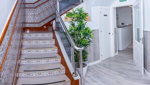 A staircase with ornate tiles, a metal handrail, and a potted plant. - Hostal Guillot (Torremolinos)