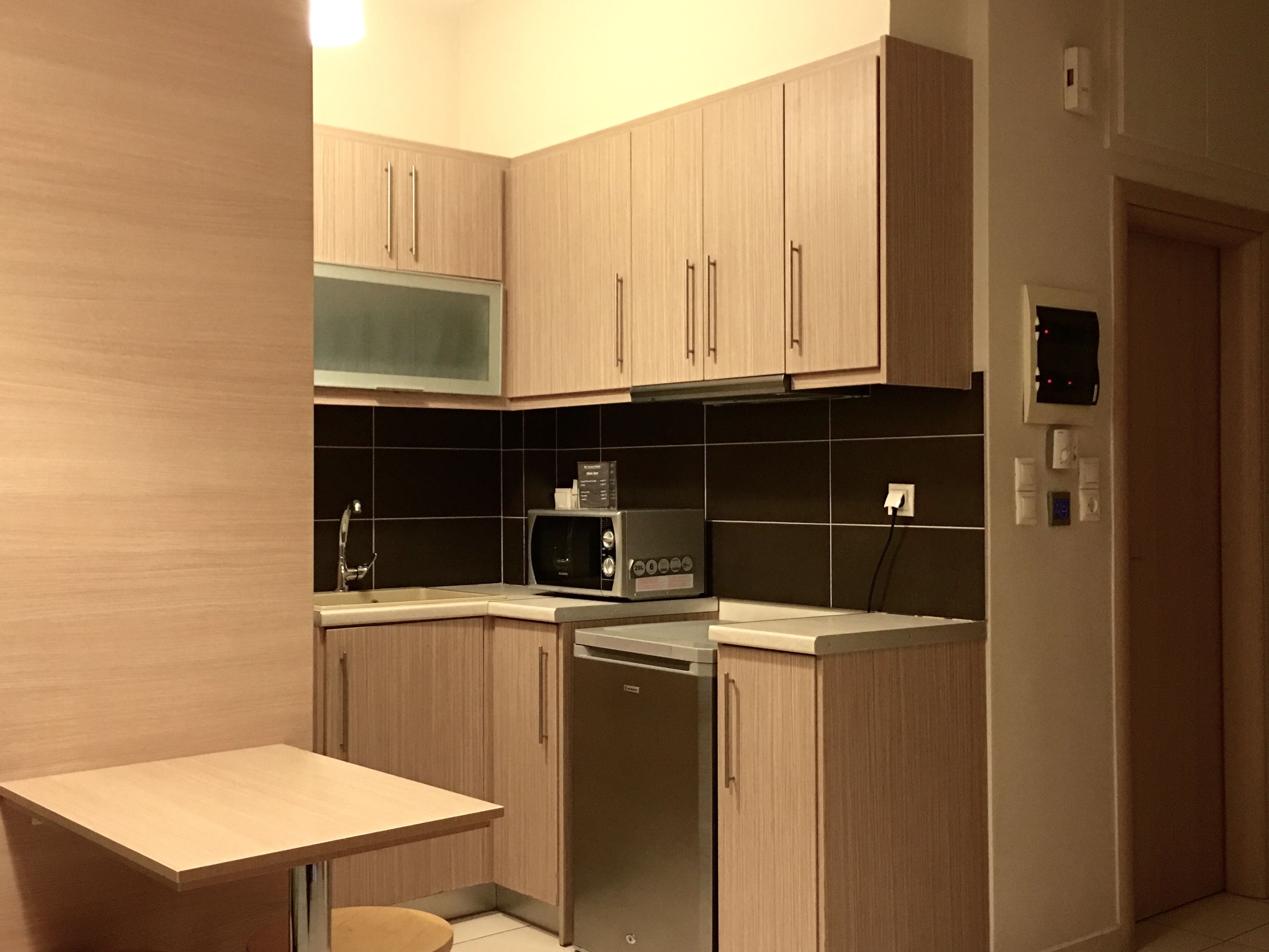 A modern kitchen with wooden cabinets, a microwave, a dishwasher, and a small table.