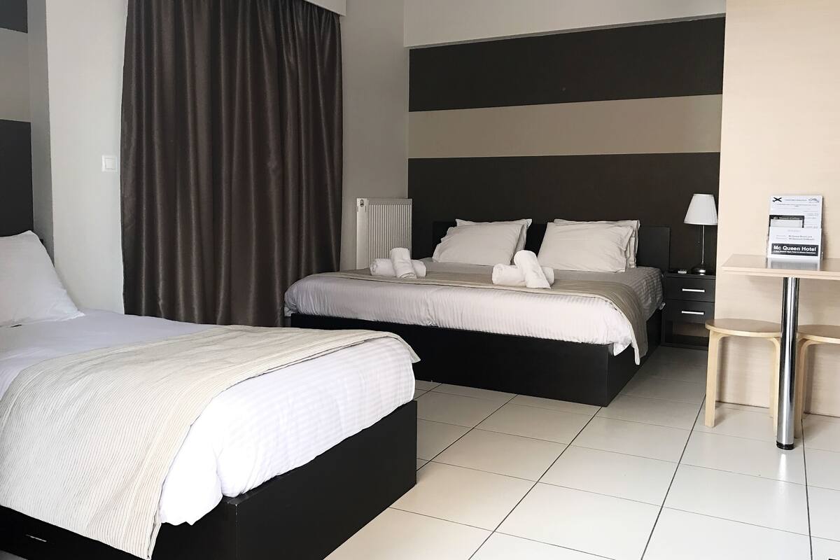 A hotel room with two beds, a desk, and a chair.