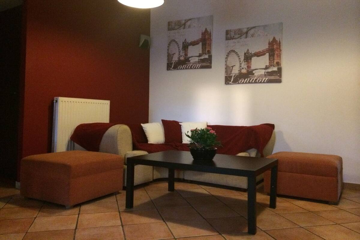 A living room with a sofa set, a coffee table, and two wall-mounted pictures of London landmarks.