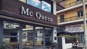 A building with a sign reading "Mc Queen" and another sign in a foreign language.