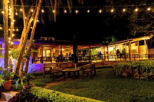 An outdoor dining area with string lights, wooden benches, and tables.