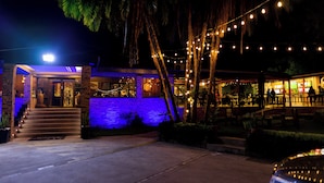 A building with a stone facade, a blue-lit entrance, and outdoor seating area with string lights. - Casa Mia (Blantyre)
