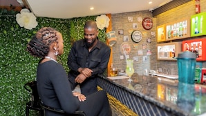 A bar area with a green wall, bar counter, and various liquor bottles. - Casa Mia (Blantyre)