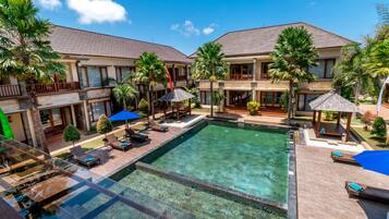 Relax by the resort's central pool, surrounded by a deck and lush palm trees.