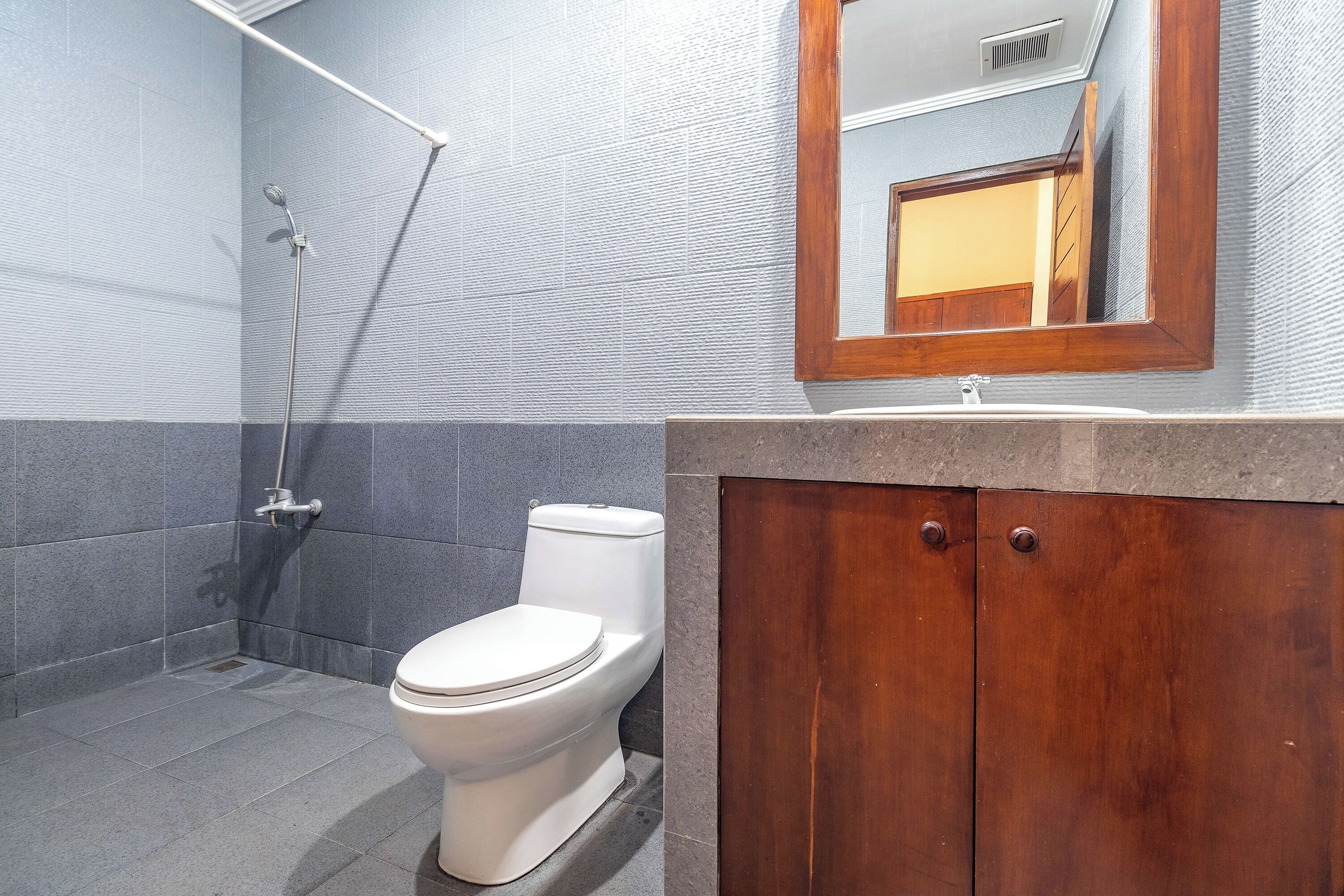 A bathroom with a shower, toilet, and wooden vanity.