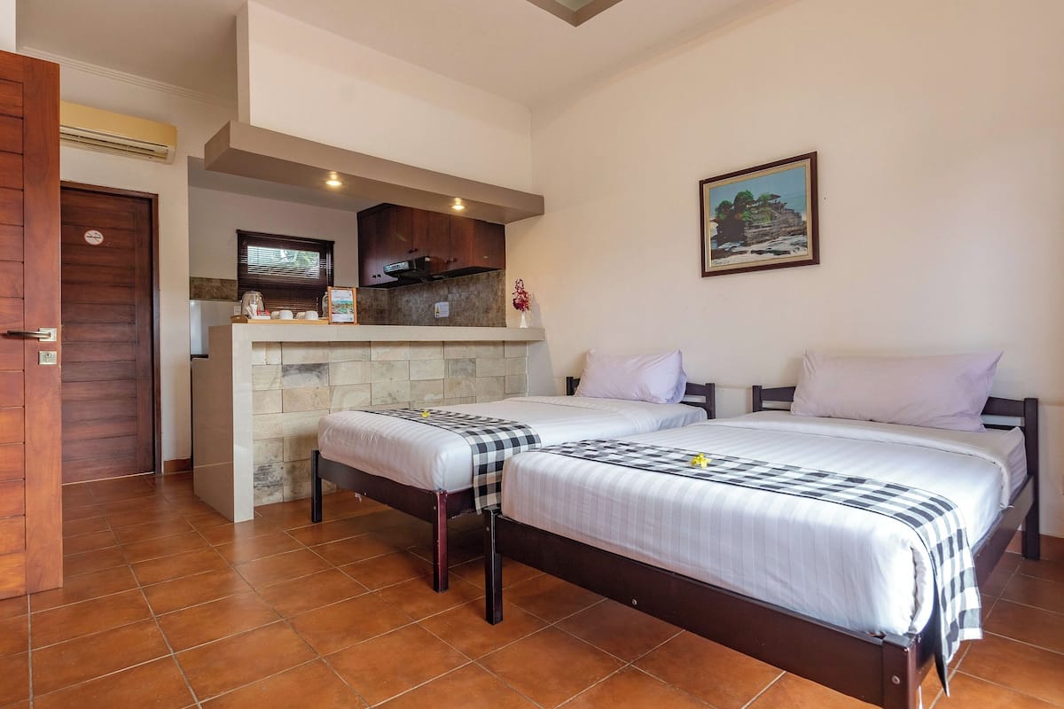 Una habitación con dos camas, kitchenette y baño.