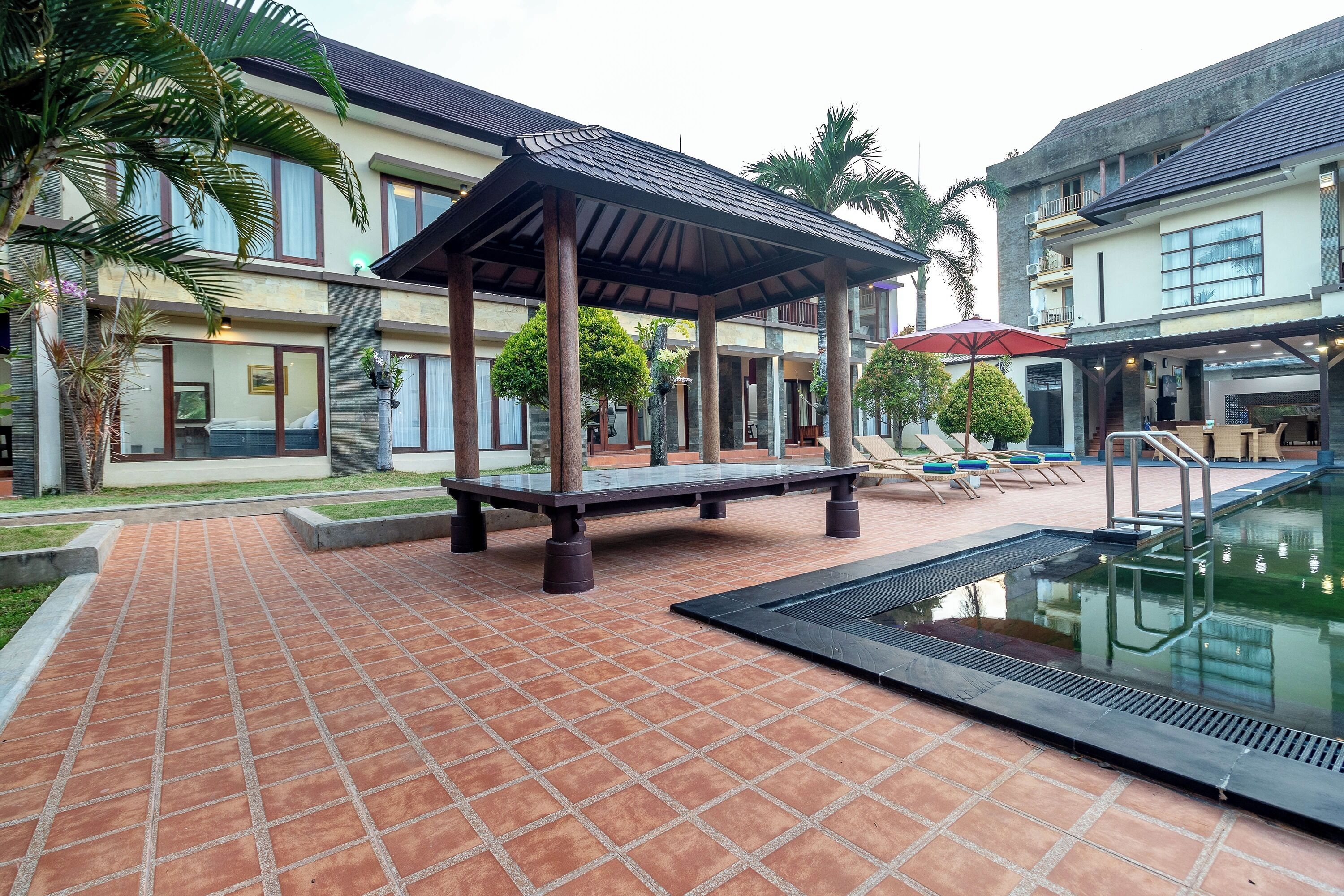 A pool area with a tiled deck, a covered seating area, and a pool with a black edge.