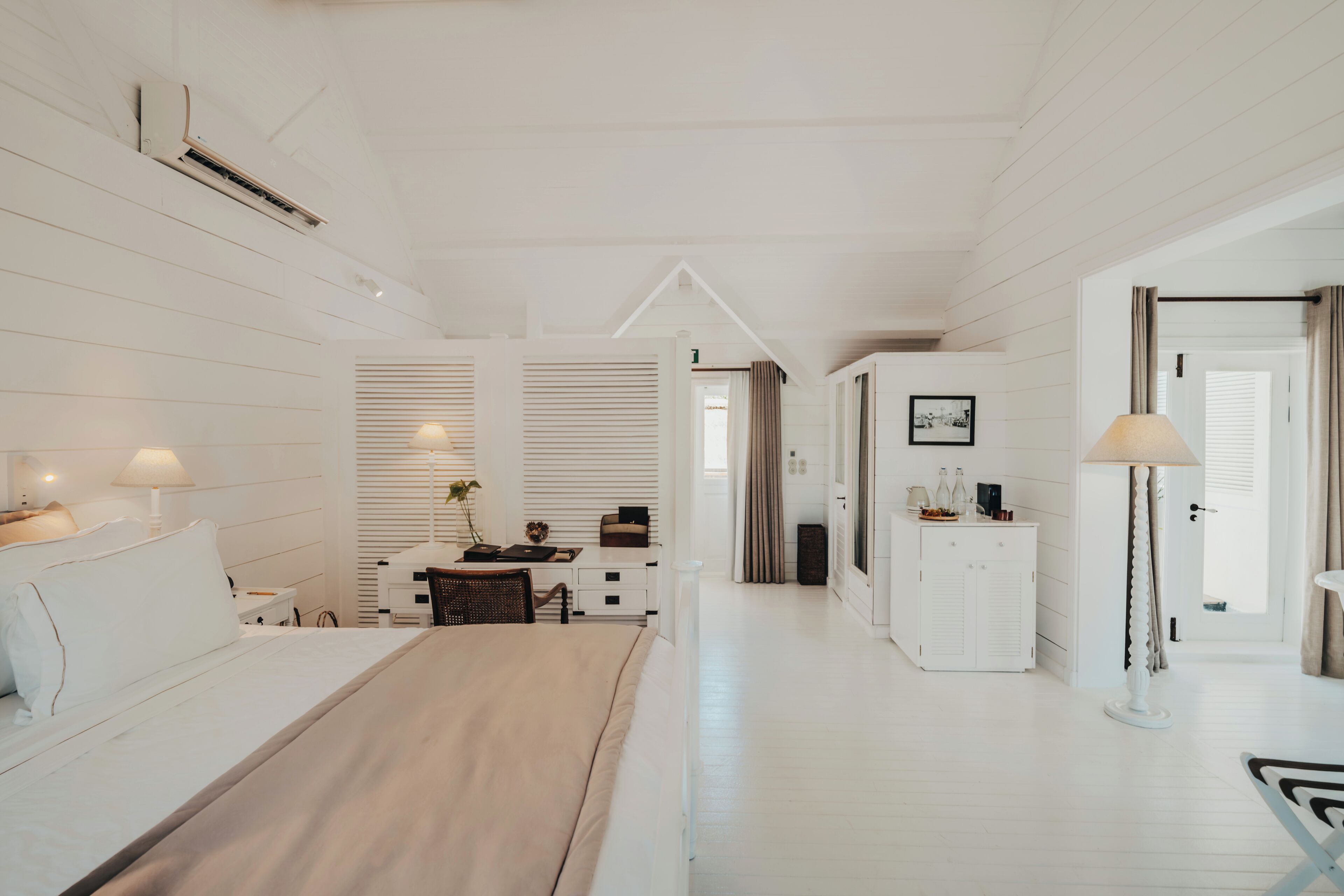 Una habitación de hotel con cama, mesita de noche, lámpara y escritorio con silla.