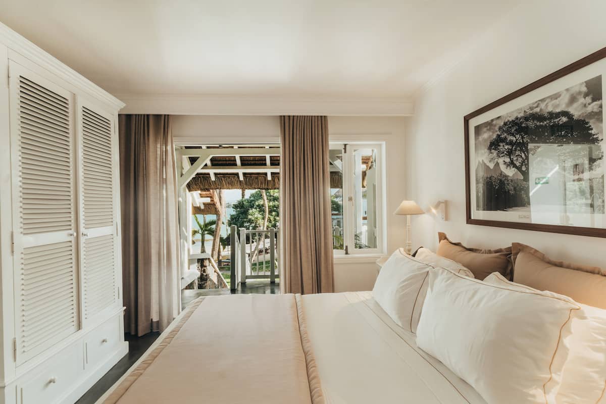 A bedroom with a large bed, a view of the outdoors, and a framed picture on the wall.