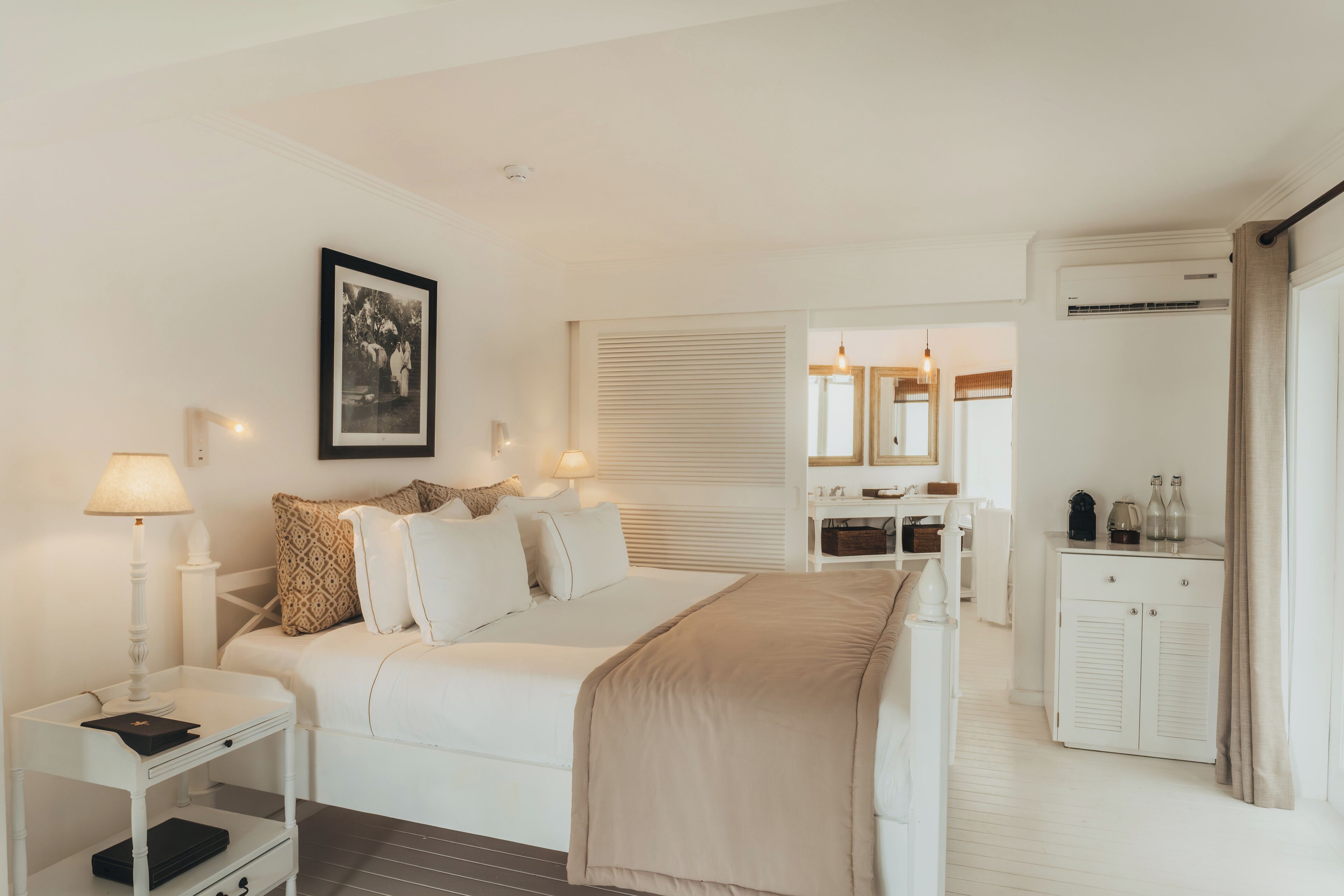A hotel room with a bed, bedside table, lamp, wardrobe, and a mirror.