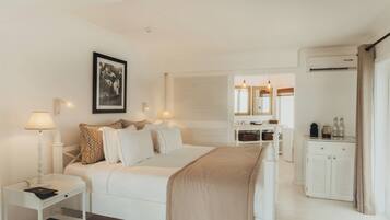 A hotel room with a bed, bedside table, lamp, wardrobe, and a mirror.