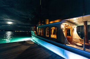 Un barco con zona de comedor cubierta y vista al océano de noche.