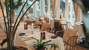 Un restaurante con mesas dispuestas para comer, con manteles blancos, sillas y un centro de mesa con velas.