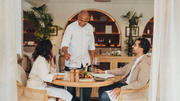 A dining area with a round table, chairs, and a waiter serving food.