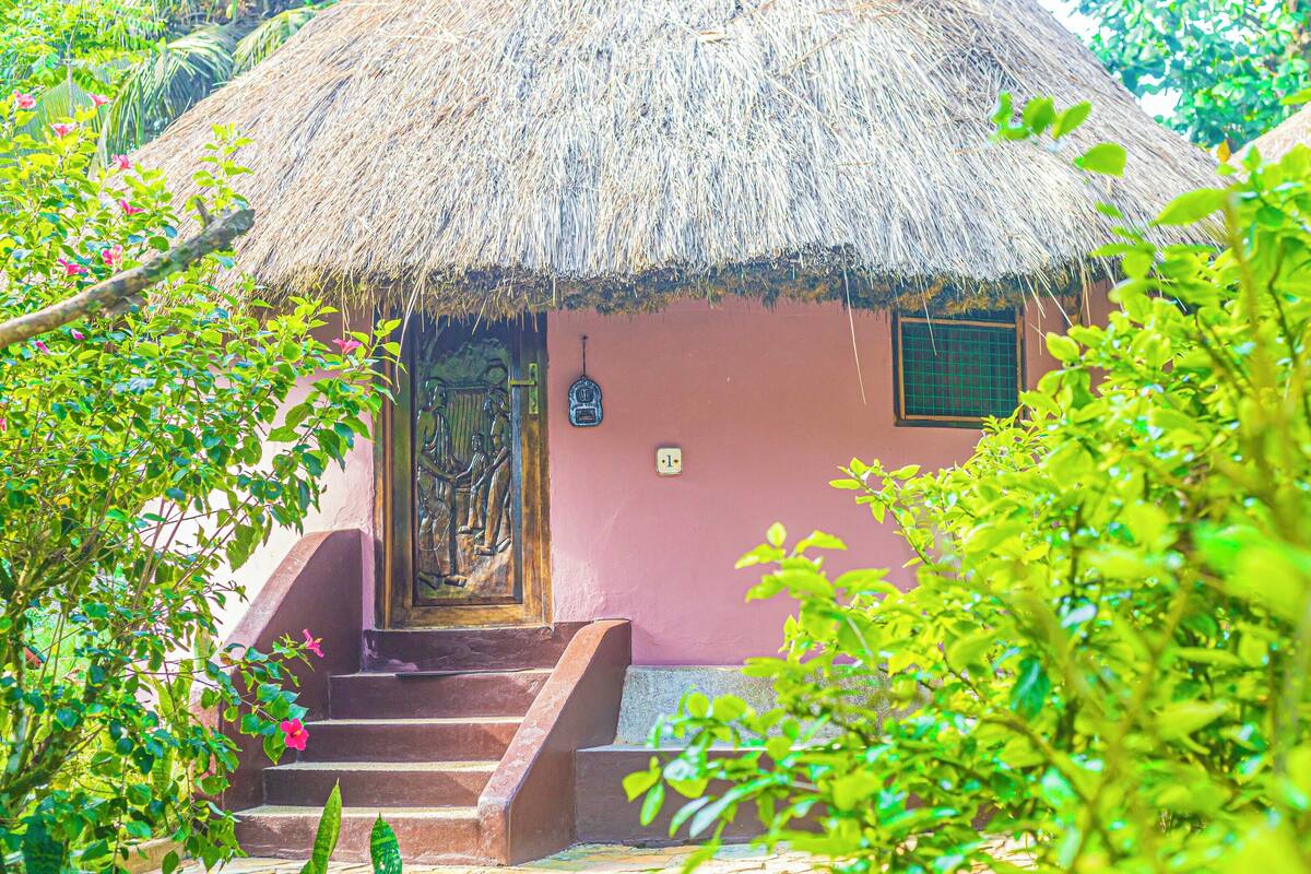 A rustic house with a thatched roof, a wooden door, and a small window.