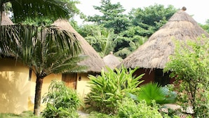 Un jardin tropical avec des huttes aux toits de chaume, des palmiers et une végétation luxuriante.