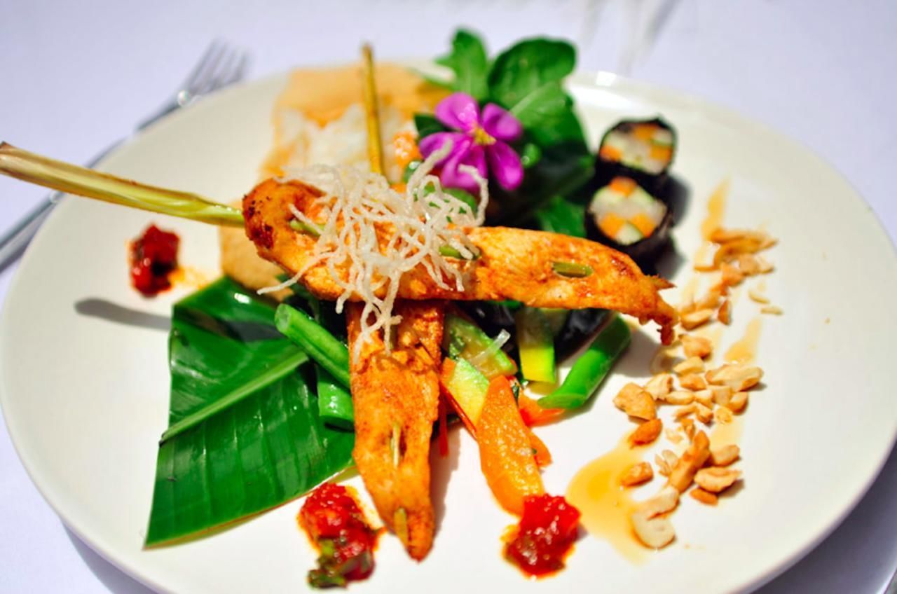A plate of food with grilled chicken, vegetables, and a flower garnish.