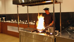 Ein Koch bereitet Essen auf einem tragbaren Herd mit einer Flamme in einer modernen Küche zu.