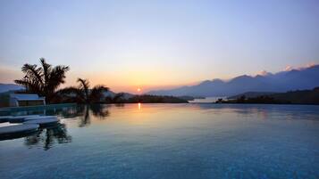 Relax by the serene pool surrounded by palm trees and majestic mountains.