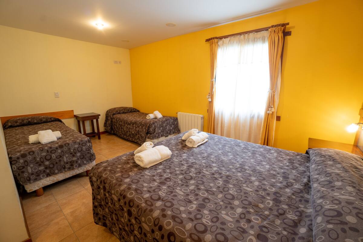 Habitación de hotel con dos camas, cada una con una colcha estampada y toallas enrolladas.